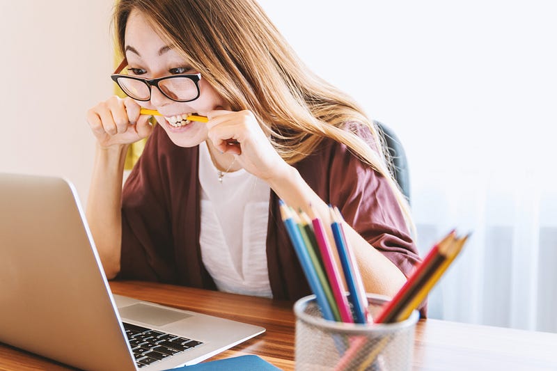 A woman nervously  biting a pencil in her mouth
